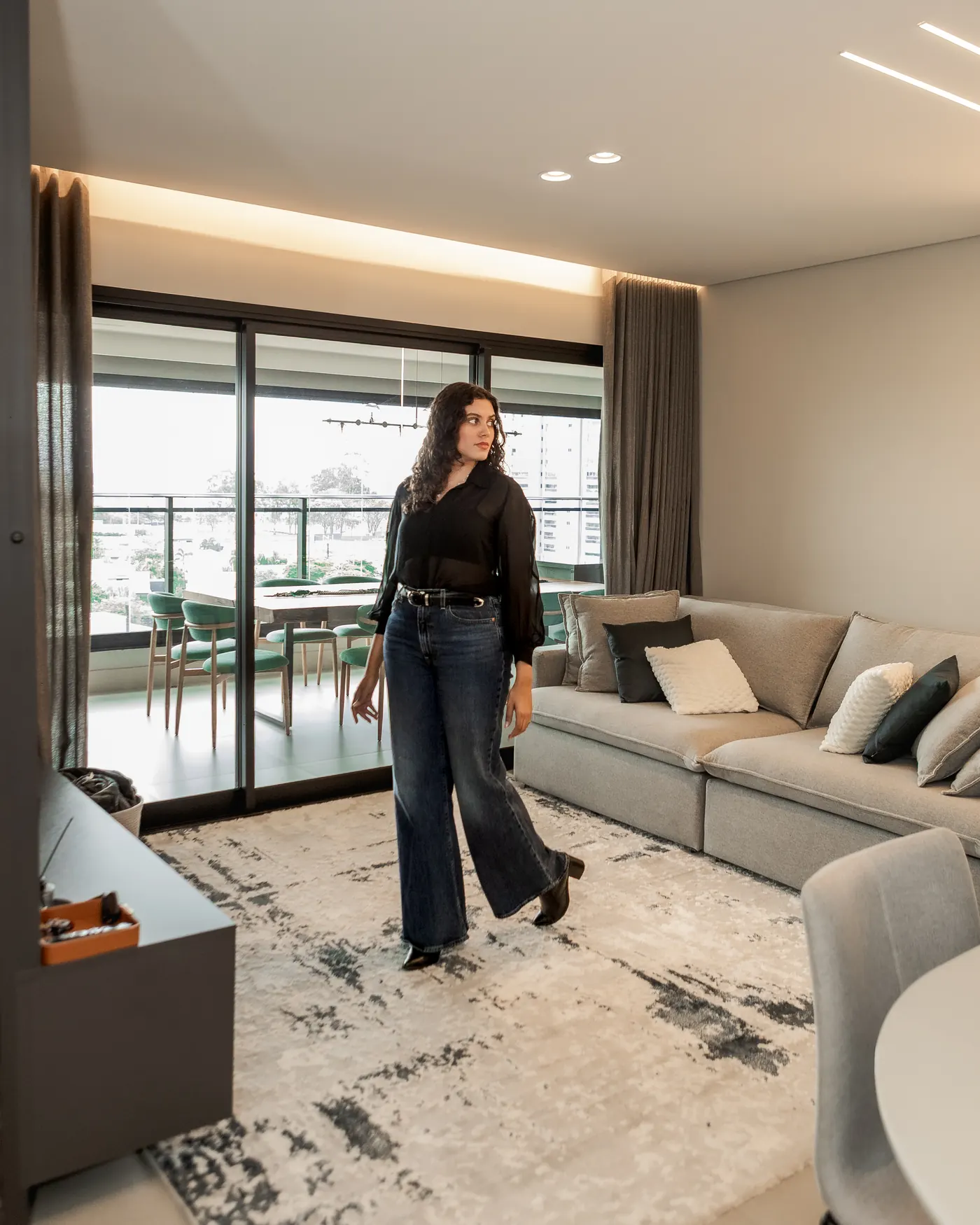 Talyssa Jade caminhando pela sala de estar, com a varanda gourmet ao fundo