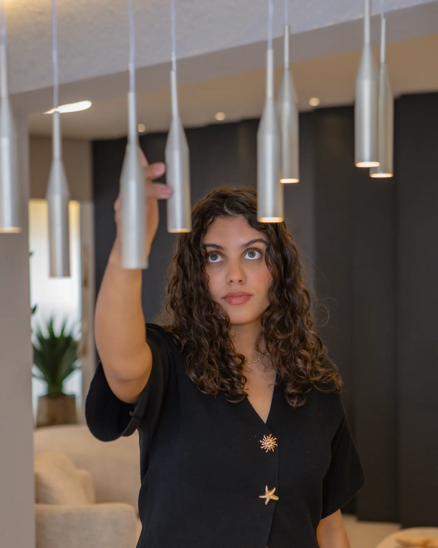 Talyssa Jade ajustando os pendentes metálicos sobre a mesa de jantar